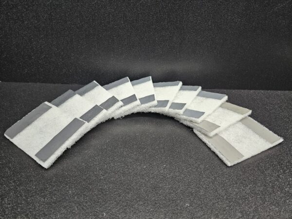 A curved array of rectangular fabric samples in various shades of gray and white displayed against a dark Acrylic Scratch Removal Kit (A).