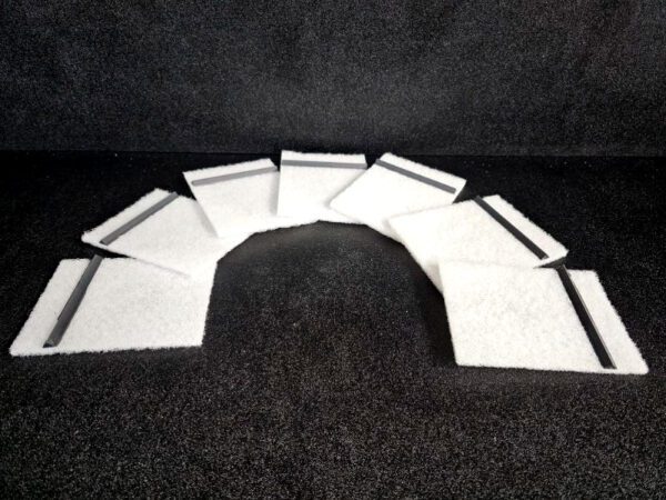 Seven rectangular white Scrub Pad (A) with black lines are arranged in a semi-circular pattern on a dark surface.