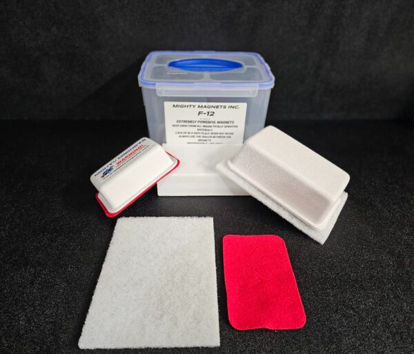 A plastic container labeled "Mighty Magnets Inc. F-9 1-3/4″ (4.4 cm) to 2-1/4″ (5.7 cm)" with a blue lid, surrounded by foam pads and a white cleaning cloth.