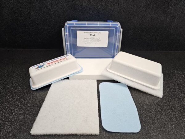 A blue and clear plastic case labeled "F-4 for 1/2″ (1.3 cm) to 1″ (2.5 cm)" with white foam pads and two rectangular filters placed in front of it on a black surface.