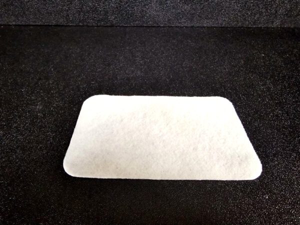 Rectangular white Scrub Pad (A) with slightly rounded corners placed on a black surface.