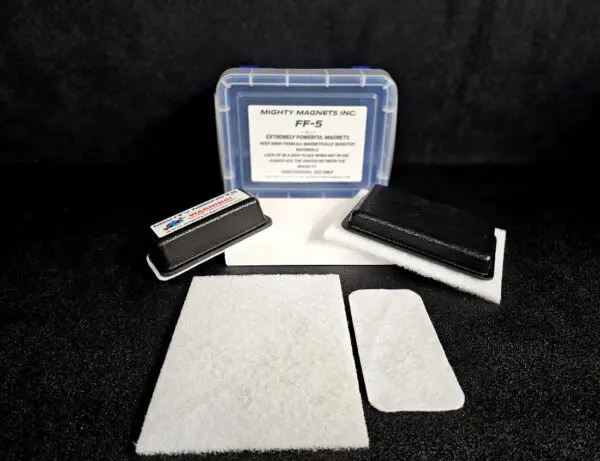 A blue plastic case labeled “FF-5 for 5/8″ (1.58 CM) TO 1-1/4″ (3.2 CM)” with two rectangular magnets and white padding material placed in front on a black background.